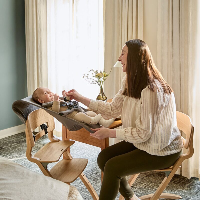 Mama z dzieckiem w foteliku Leander Newborn Seat przy stole
