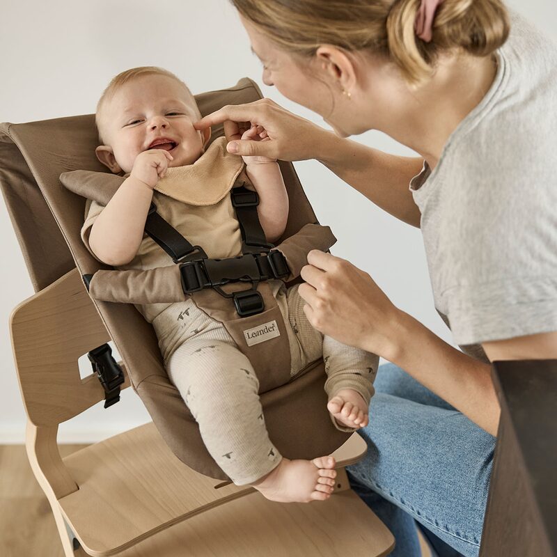 Leander Newborn Seat Mocca — miminko w foteliku przy stole z mamą