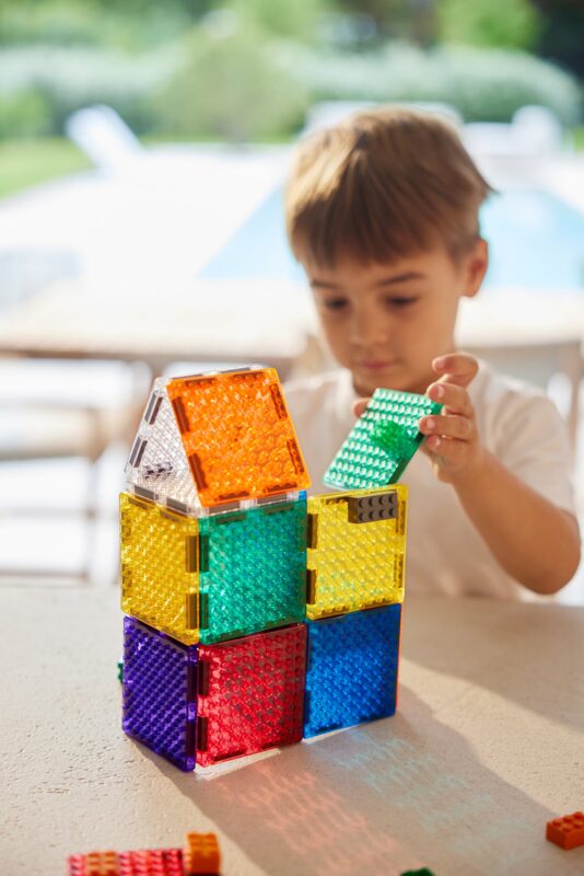 Dítě spojující magnetické kostky Cleverclixx Brick Tiles s kostkami Lego a Duplo
