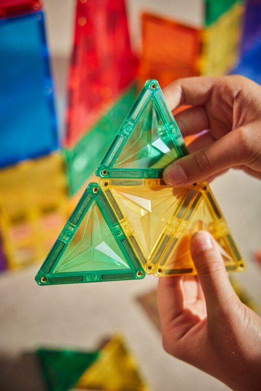 Dítě stavící barevnou konstrukci z magnetických kostek Cleverclixx Inventive Pack Intense